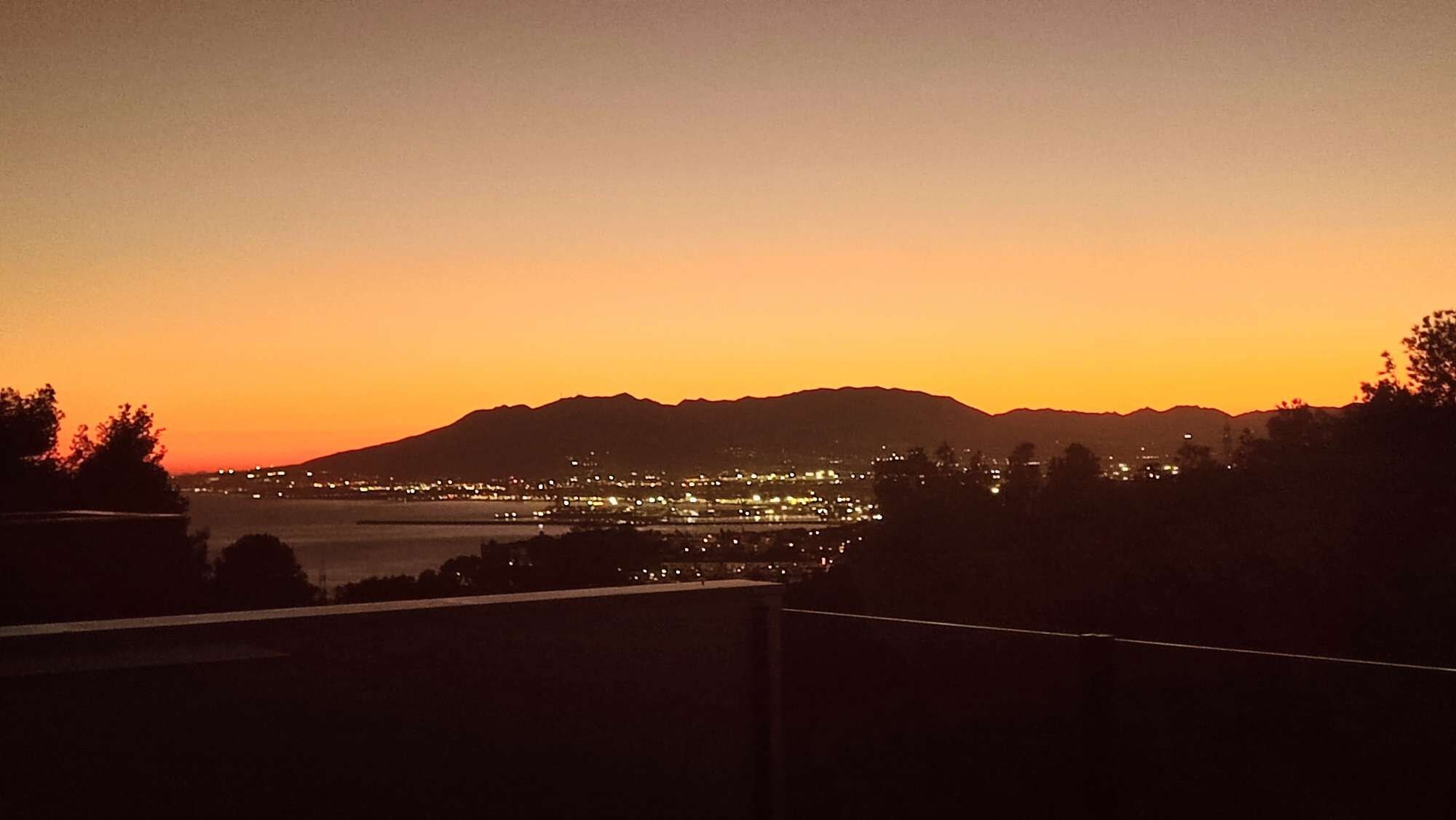 A cityscape at dusk with a mountain in the background.