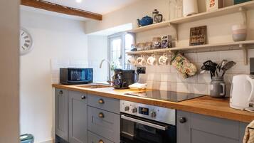 Una cocina con microondas, cafetera y un reloj en la pared.