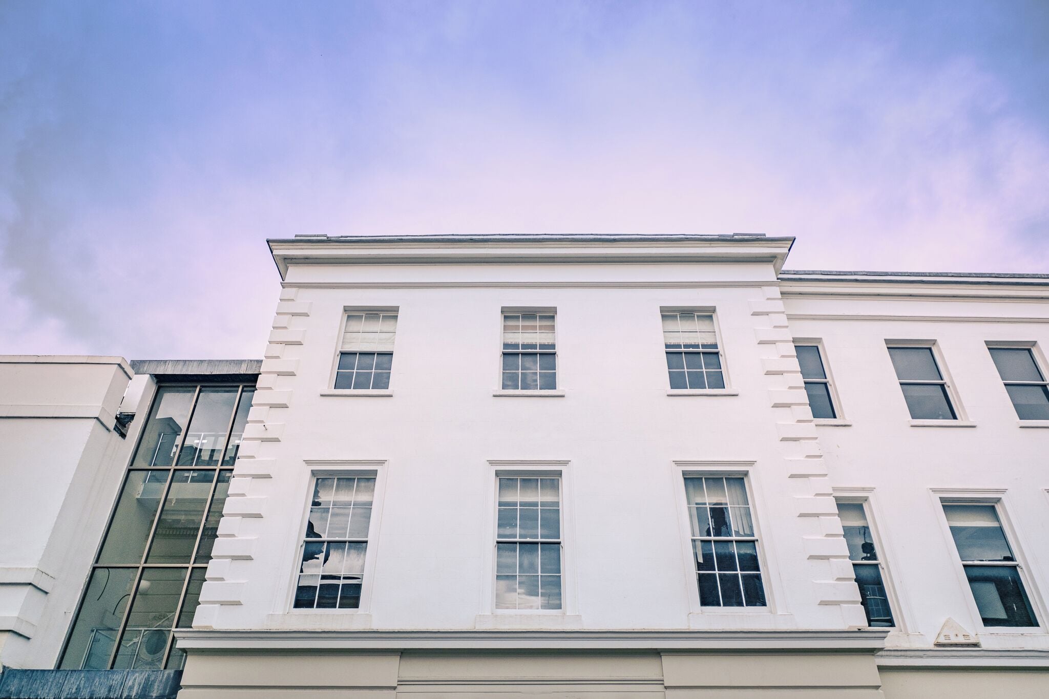 A multi-story building with a white facade and multiple windows.