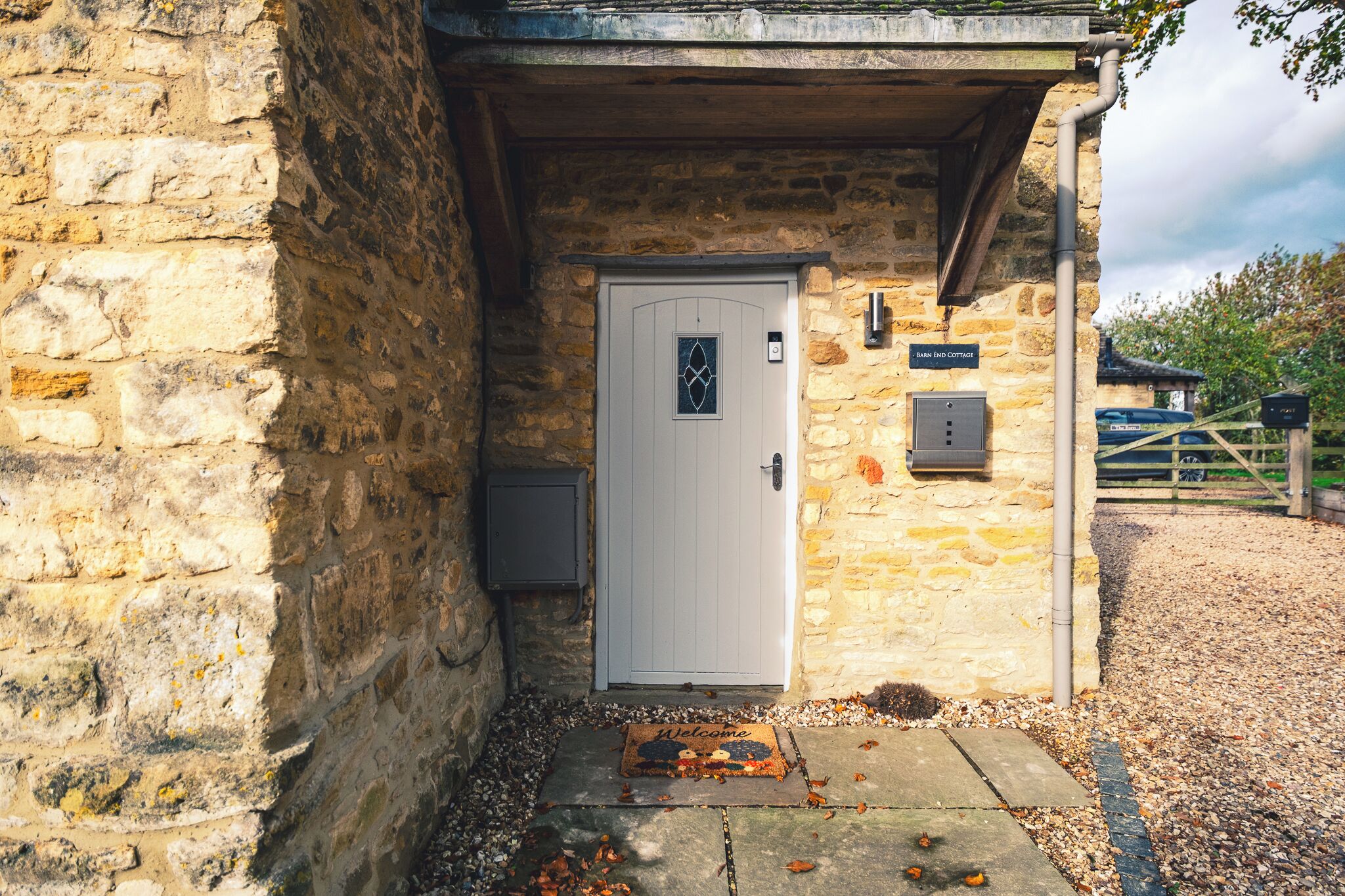 Ein Steingebäude mit einer weißen Tür, einer Fußmatte und einem Schild mit der Aufschrift 'Brew Cottage'.