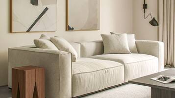 Ein modernes Wohnzimmer mit einem beigen Sofa, einem Holztisch und einer Stehlampe.