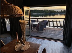 A room with a view of a lake, a dining table with chairs, and a wicker chair. - Kustvy - A seaside Destination (Hållnäs)