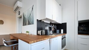 A modern kitchen with a wooden countertop, a Bosch refrigerator, a coffee maker, and a microwave. - Beautiful Studio in Middle of Downtown (Turku)