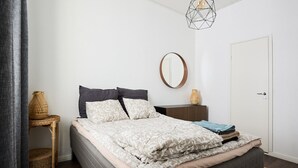 Une chambre à coucher avec un lit, une table de chevet et un luminaire suspendu.