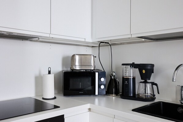A modern kitchen with a microwave, coffee maker, and kettle. - Modern 1BR Apt. in Turku with Best Location (Turku)