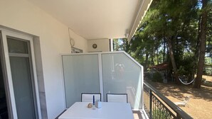 A balcony with a table and chairs, a glass partition, and a view of trees and a hammock. - Couples Warm Nook - Thassos Seabreeze Nest (Thasos)