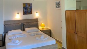 Una cama bien hecha con toallas, una lámpara de noche y un cuadro en la pared.