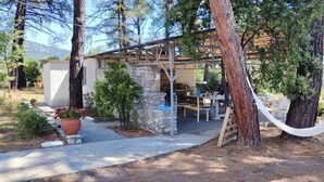 Un área de estar rústica al aire libre con paredes de piedra, una pérgola de madera y una hamaca.