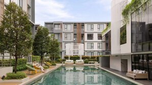 A modern residential building with a swimming pool, outdoor seating, and greenery. - Luxury Brand-new Apt in Low-Density Villa, Pool View near the Old town & Airport (Pa Daet Sub District , Mueang District)