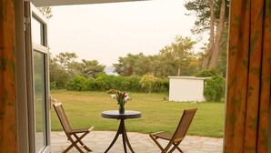 A dog lying on a mat at the entrance of a room with a view of a garden and patio furniture. - Anatoli Garden View - Cozy Thassos Getaway (Thasos)