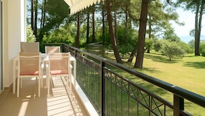 Een balkon met uitzicht op een gazon en hoge bomen.