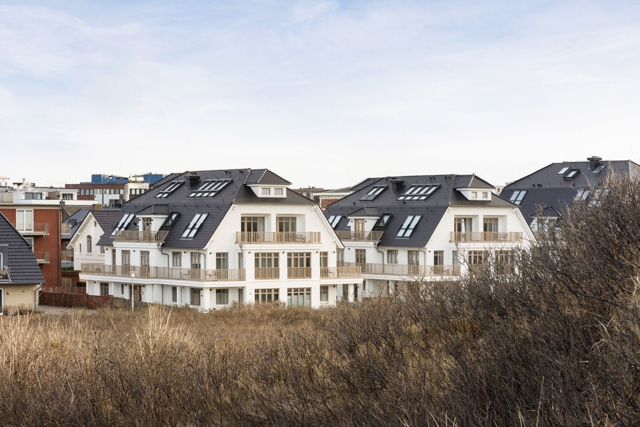 Une rangée d’immeubles résidentiels modernes, dotés de plusieurs étages, de grandes fenêtres et d’un toit plat.