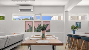 Un espace repas moderne avec une table en bois, des chaises blanches et un canapé gris.