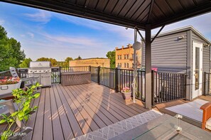 A covered outdoor deck with a grill, seating, and a small shed. - Downtown condo with private rooftop patio. Downtown Grand Forks. (Grand Forks)