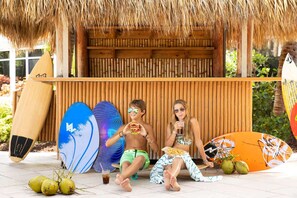 Tropische omgeving met een rieten dak, houten wand en surfplanken.