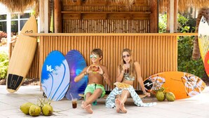 A tropical setting with a thatched roof, wooden wall, and surfboards. - Sunny Retreat | Restaurant + Outdoor Pool (Hollywood)