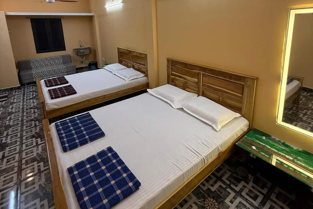 A hotel room with two beds, a ceiling fan, a small table, a mirror, and patterned flooring.