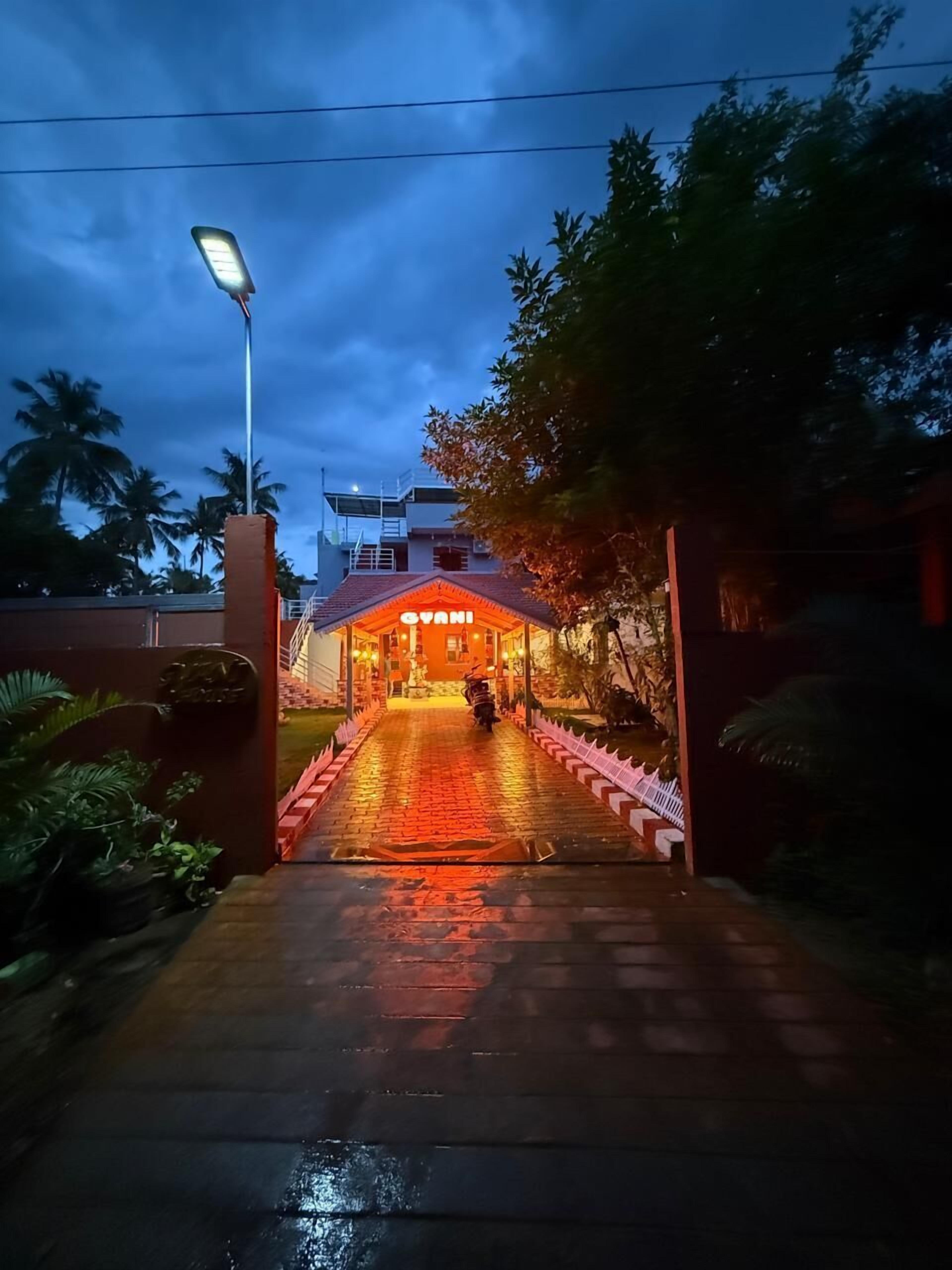 A hotel entrance with a paved pathway leading to a building with a sign that reads "GYANI".