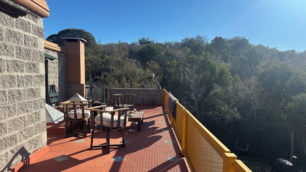 A terrace with outdoor seating, a barbecue grill, and a view of a forested hillside. - Bell Vivere Guesthouse (El Volcan)