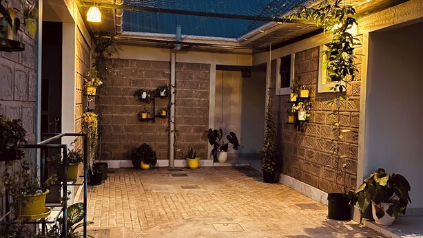 A courtyard with brick flooring, potted plants, and a metal fence. - Kili Haven Lodge (Moshi)