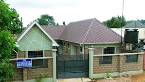 A lodge with a gated entrance, a signboard, and a brick wall. - Kili Haven Lodge (Moshi)