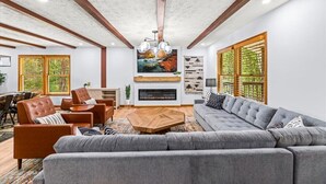 Ein modernes Wohnzimmer mit Kamin, Sitzecke und großen Fenstern.
