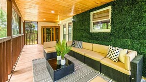 Ein überdachter Außenbereich mit grüner Wand, einer Couch und einem Couchtisch.