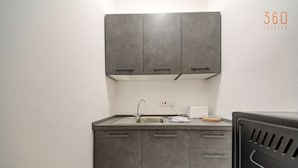 A compact kitchen with dark cabinets, a stainless steel sink, and a toaster on the countertop. - Bright Msida Studio · King Bed - Fast WiFi (Msida)