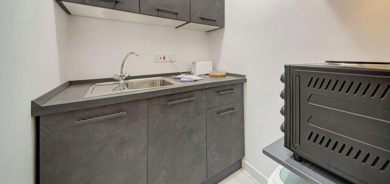 Una cucina compatta con lavello in acciaio inox, piano cottura integrato e un piccolo bancone.
