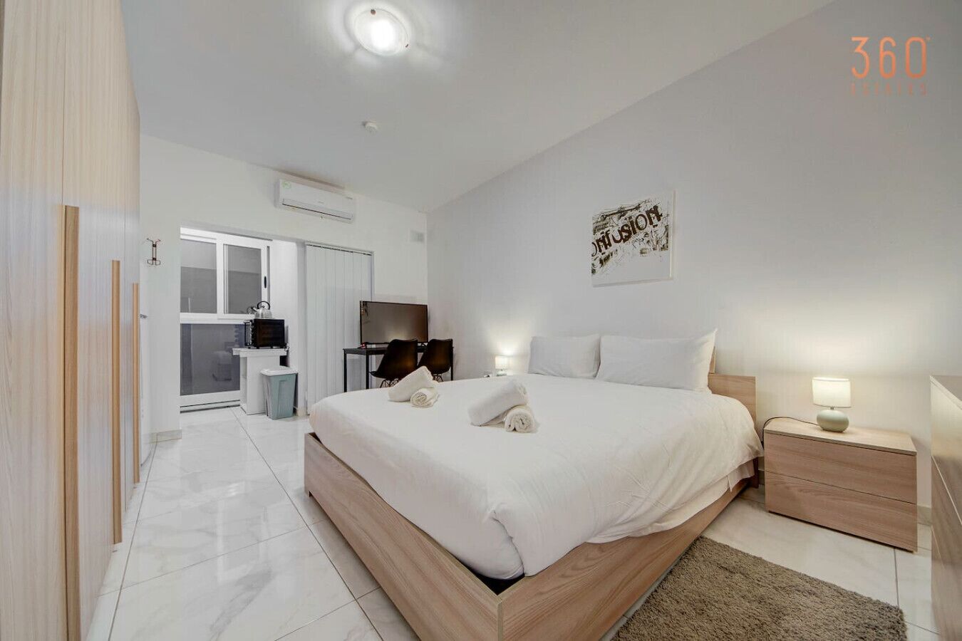 Una camera d'albergo moderna con un letto grande, comodini, una scrivania e una televisione.