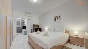 Ein modernes Hotelzimmer mit einem großen Bett, Nachttischen, einem Schreibtisch und einem Fernseher.
