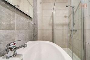 A bathroom with a white sink, a glass shower enclosure, and tiled walls. - 1BR home with fully amenities, WIFI & AC in Msida (Msida)