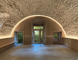 Ein gewölbter Raum mit einer rauen Steinwand und Holzlatten.