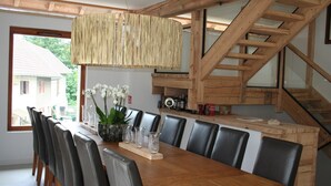 Un espace repas avec une table en bois, des chaises noires et un luminaire suspendu.