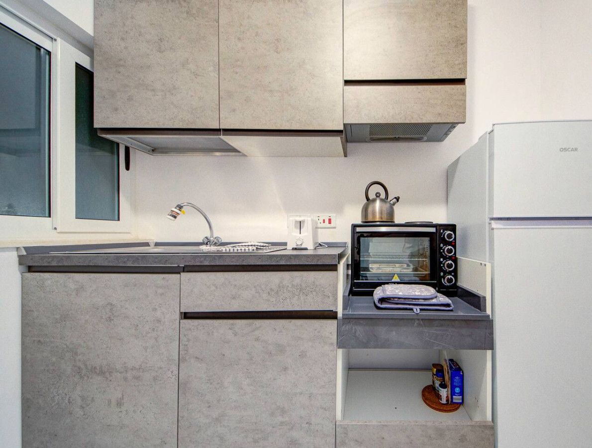 Una cucina compatta con forno a incasso, bollitore e tostapane.