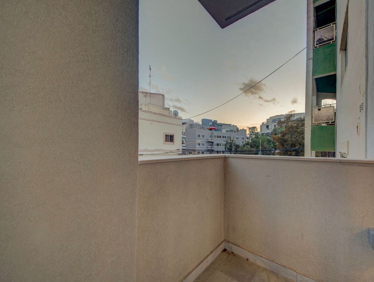 Un balcone con vista sugli edifici circostanti e un cielo sereno.
