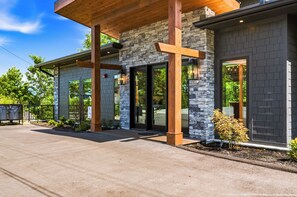 A modern building with stone and wood exterior, large glass doors, and a covered entrance. - Beneath the Stars | Luxury 3BR Cabin w/ Indoor Pool & Game Room (Gatlinburg)