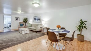 A modern living room with a dining area, featuring a sofa, coffee table, and a dining table with chairs. - Walk to Shops at Belmar: Denver Area Home Base (Lakewood)