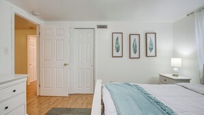 A bedroom with a bed, a nightstand, a dresser, and a door leading to another room. - Walk to Shops at Belmar: Denver Area Home Base (Lakewood)