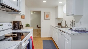 A modern kitchen with white cabinets, a built-in oven, a microwave, and a sink. - Walk to Shops at Belmar: Denver Area Home Base (Lakewood)