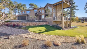A large, multi-story house with a stone facade, a covered patio, and a well-maintained lawn. - Hot Tub & Games Galore! Colorado Springs Retreat (Colorado Springs)