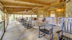 A wooden deck with outdoor seating, a stone wall, and a door labeled "La Vida Lo Cove." - Creekside Cabin in the Heart of Maggie Valley (Maggie Valley)