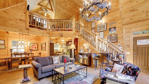 A spacious wooden cabin interior with a dining area, living room, and a staircase leading to an upper level. - Creekside Cabin in the Heart of Maggie Valley (Maggie Valley)