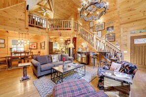 A spacious wooden cabin interior with a dining area, living room, and a staircase leading to an upper level. - Creekside Cabin in the Heart of Maggie Valley (Maggie Valley)