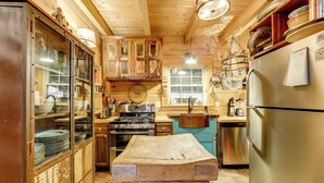 A rustic kitchen with wooden cabinets, a large wooden table, a stainless steel refrigerator, and a stove. - Creekside Cabin in the Heart of Maggie Valley (Maggie Valley)