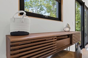 Una consola de madera con un bolso tejido y un pequeño adorno.