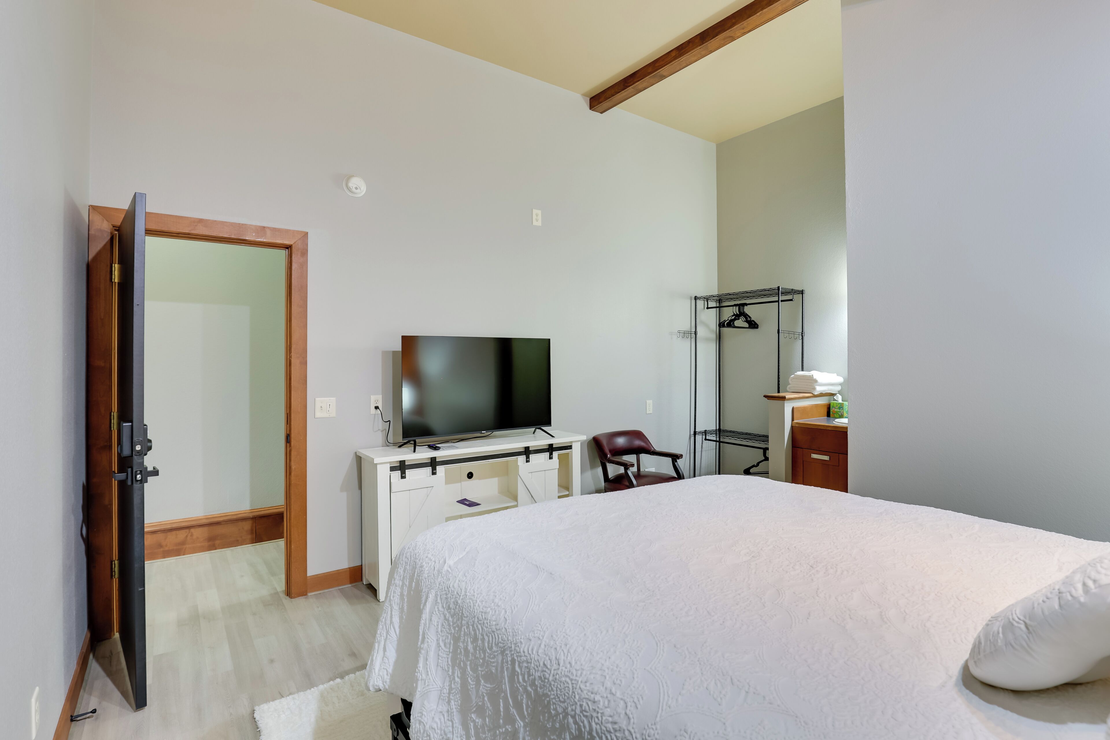 Ein Schlafzimmer mit Bett, Fernseher, Schreibtisch und Kleiderschrank.