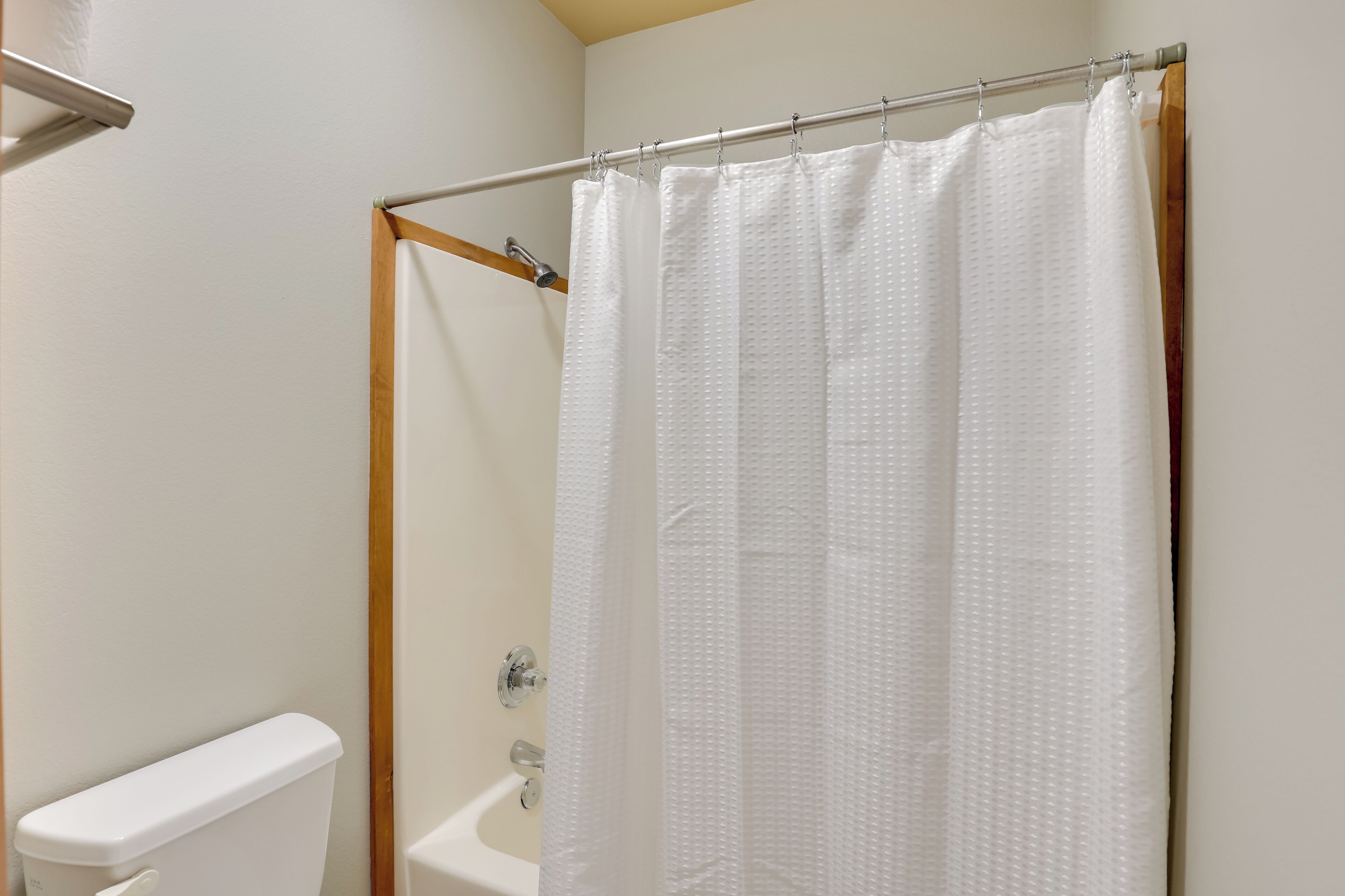 Un baño con cortina de ducha blanca, inodoro y bañera.