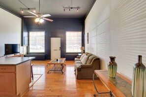 A spacious living area with a wooden floor, a sofa, a coffee table, and a TV.