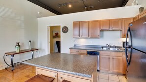 A kitchen with wooden cabinets, a granite countertop, and a stainless steel refrigerator. - Steps to Restaurants & Shops! Dtwn Marshall Apt (Marshall)
